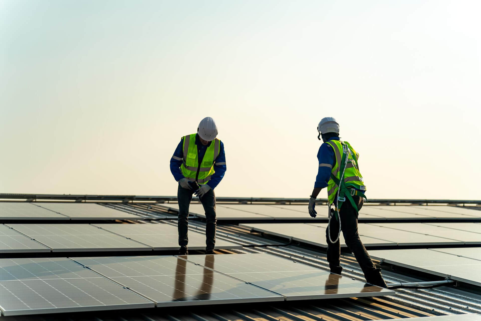 PlayGreenin aurinkopaneeliasentajat työskentelemässä kattolla auringonlaskun aikaan – älykkään energian asennus Suomessa, erityisesti Etelä-Suomessa